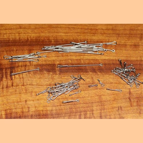 Three piles of silver-colored nails on a wooden surface.