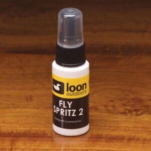 A small bottle of Loon Fly Spritz 2 on a wooden surface.