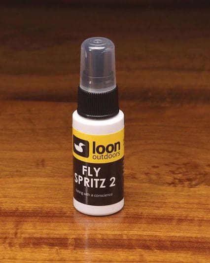 A small bottle of Loon Fly Spritz 2 on a wooden surface.