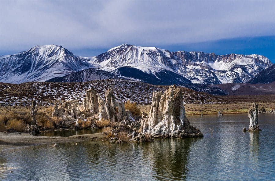 A collection of shiny metallic chess pawns arranged on a peach background.