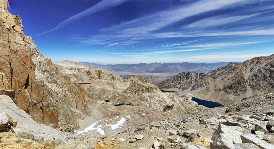 A collection of shiny metallic chess pawns arranged on a peach background.