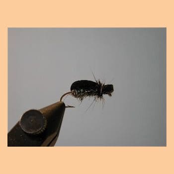A close-up of a fishing fly lure held by tweezers.
