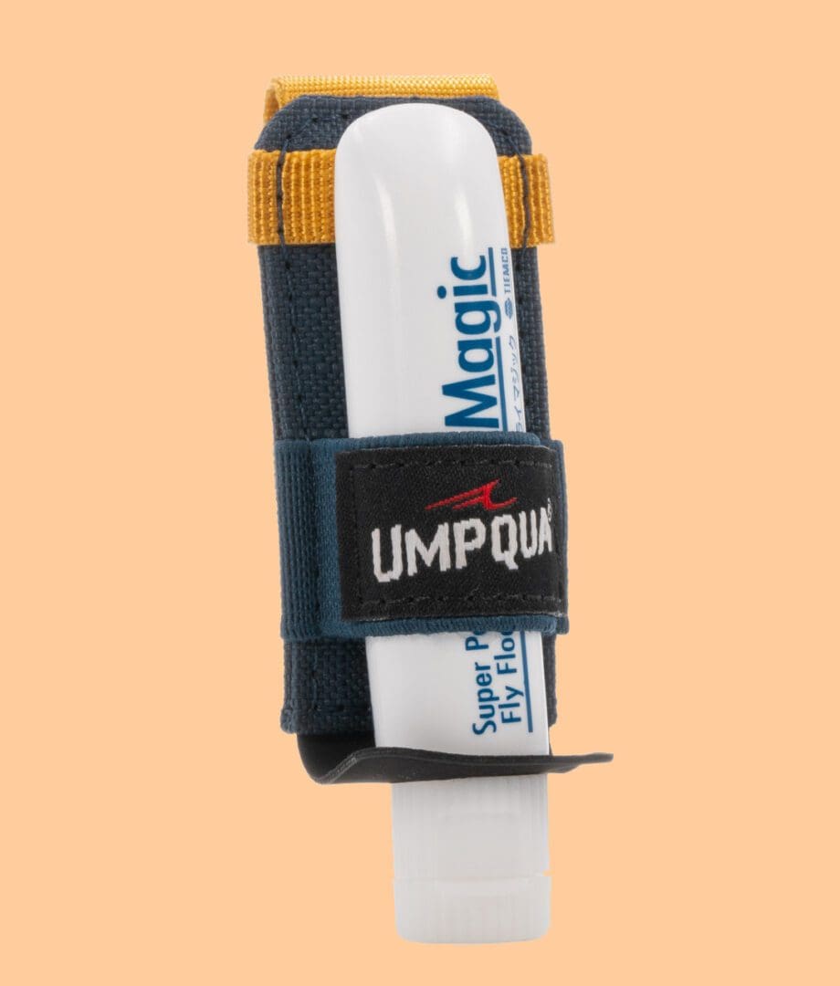 A hockey stick with a black Umpqua grip and white Magic sticker on an orange background.