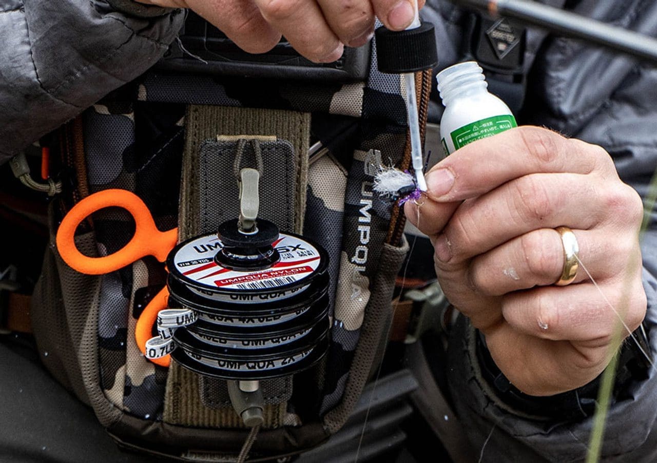 Person refilling car windshield washer fluid with a green nozzle.